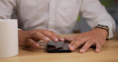 Close up hand of Business man touching smartphone on table. Man using helpful mobile apps for business time management organization while sitting at work desk. Business and technology concept. video