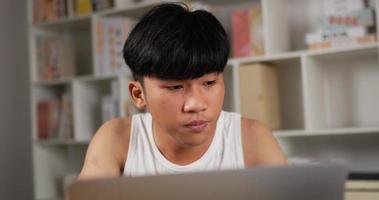 close-up van aziatische man in hemd die werkt en niest terwijl hij thuis zit. ziek en vermoeid mannetje dat laptop met behulp van aan bureau. thuiswerken 's nachts overbelast in het nieuwe normaal.