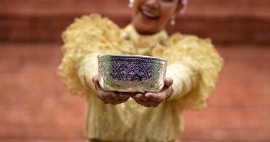 nahaufnahme, selektiver fokus die hand der jungen schönen frau in thailändischer traditioneller tracht reichte ihr eine schüssel wasser auf dem songkran-fest, dem thailändischen neujahr, dem familientag im april