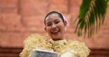primer plano, enfoque selectivo joven mujer hermosa en traje tradicional tailandés entregó un tazón de agua frente a ella en el festival de songkran, año nuevo tailandés, día de la familia en abril