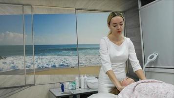 A masseur gives a woman a professional facial massage. The massage room performs a rejuvenation procedure. High quality Full HD footage video