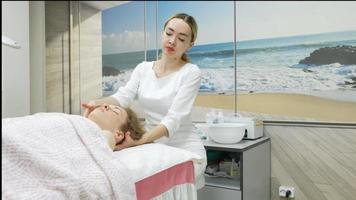 een masseur geeft een vrouw een professionele gezichtsmassage. de massageruimte voert een verjongingsprocedure uit. hoge kwaliteit full hd-beelden