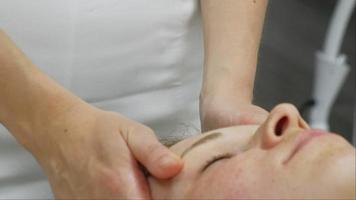 Ein Masseur gibt einer Frau eine professionelle Gesichtsmassage. Der Massageraum führt eine Verjüngungsprozedur durch. Full-HD-Aufnahmen in hoher Qualität video