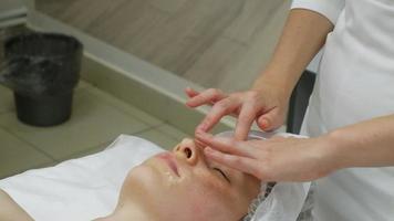 un masseur donne à une femme un massage facial professionnel. la salle de massage effectue une procédure de rajeunissement. images Full HD de haute qualité