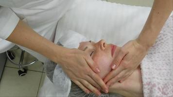 A masseur gives a woman a professional facial massage. The massage room performs a rejuvenation procedure. High quality Full HD footage video