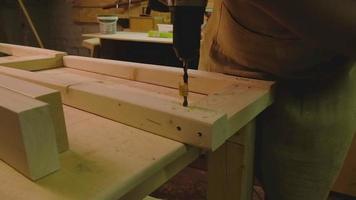 The master makes holes with a drill in wood parts video