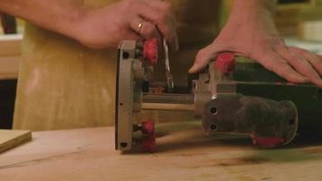 A master mature man prepares a milling cutter for working with boards