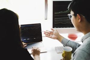 An investment expert points a pen at a computer monitor to analyze the stock market to teach you how to make a profit. photo