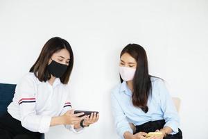 social distancing concept, Two women wearing masks and distancing while sitting on mobile phones following coronavirus social trend. photo