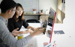 An investment expert points a pen at a computer monitor to analyze the stock market to teach you how to make a profit. photo