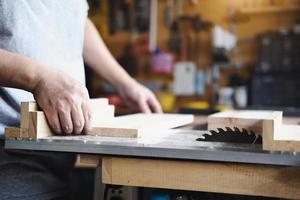 Woodworking practitioners use saw blades to cut wood pieces to assemble and build wooden tables for their clients. photo