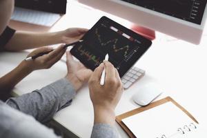 An investment expert points a pen at a computer monitor to analyze the stock market to teach you how to make a profit. photo