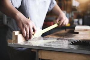 do-it-yourself concept Craftsmen use a tape measure to assemble wooden pieces to make wooden tables for customers. photo