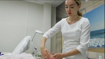 Ein Masseur gibt einer Frau eine professionelle Gesichtsmassage. Der Massageraum führt eine Verjüngungsprozedur durch. Full-HD-Aufnahmen in hoher Qualität video