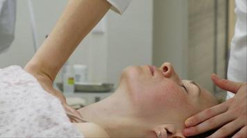 um massagista dá a uma mulher uma massagem facial profissional. a sala de massagem realiza um procedimento de rejuvenescimento. filmagem full hd de alta qualidade
