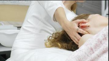 Ein Masseur gibt einer Frau eine professionelle Gesichtsmassage. Der Massageraum führt eine Verjüngungsprozedur durch. FullHD-Aufnahmen in hoher Qualität