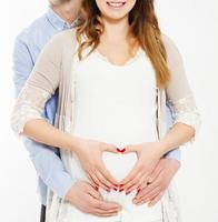 couple making a heart shape on the pregnant belly with their hands. Concept of pregnancy, expecting a baby, love, care,cropped photo