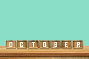 October alphabet blocks on wooden table with blue background. Copy space for text photo