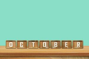 October alphabet blocks on wooden table with blue background. Copy space for text photo