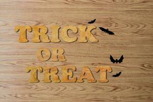 Trick or treat written with wooden letters over brown wood boards surface. photo