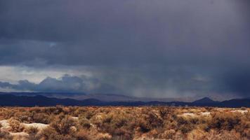 Time lapse storm clouds travel over desert and mountains