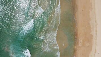 vista aérea da praia de areia branca e textura da superfície da água. ondas espumosas com céu. bela praia tropical. incrível litoral arenoso com ondas do mar branco. conceito de natureza, marinha e verão. video