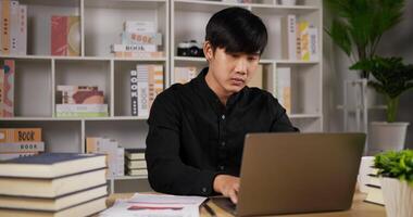 retrato de un hombre de negocios enfocado trabajando en una computadora portátil y tomando café en la oficina en casa. joven emprendedor que usa laptop estudiando en línea trabajando desde casa en internet. video