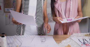 Close up hand of Two fashion designer women working in studio. Young girls coworkers talking about new design. video