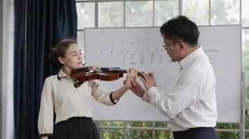 mujer adulta aprendiendo a tocar el violín en el aula de música video