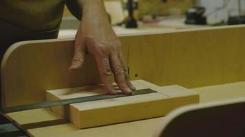 o mestre faz medições com uma régua na madeira e depois corta o excesso ao longo da linha com uma serra circular