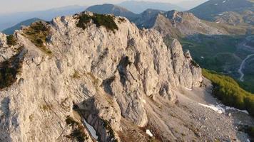 um tiro aéreo voando sobre o pico da montanha rochosa. um lindo dia de verão e uma pedra pintada com as cores do pôr do sol. video