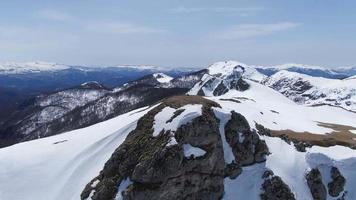 riprese aeree sulla cima della montagna in inverno. video cinematografico drone 4k. picco di montagna rannicchiato con la neve.