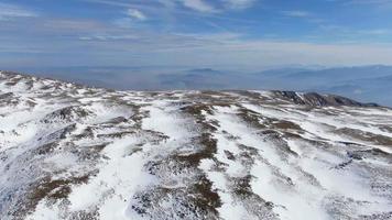 inverno su un altopiano di montagna. prati innevati, soleggiata giornata invernale. ripresa aerea di una cima di una montagna con un drone. video