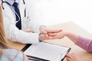 Friendly doctor hold patient hand in office. Examination result, positive test, calm down, promise and cheer up.Grief and suffer, treatment, condolence, ethics concept. photo