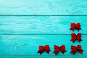 Frame of red bows on blue wooden background with copy space. photo