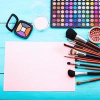 Cosmetics and accessories on blue wooden background and pink copy space. Top view and squared frame photo