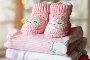 Pair of small baby socks on pink background with copy space for your warm message