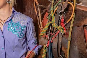 Woman saddling a horse and tighten the girth. Foreground. photo