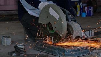 Professional men wearing goggles and construction gloves work in home workshop with angle grinder. Sanding metal makes sparks, closeup video