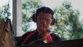 el hombre trabaja en el taller doméstico con amoladora angular, gafas y guantes de construcción. lijar metal hace chispas, primer plano
