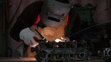 Professional men wearing welding mask and gloves work in home workshop with arc welding and argon.