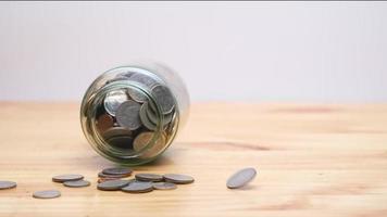 In slow motion, the coin slipped from the falling glass jar on the wooden table. Financial concept. video