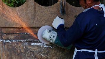 Professional men wearing goggles and construction gloves work in home workshop with angle grinder. Sanding metal makes sparks, closeup video