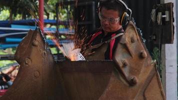 man werk in thuiswerkplaats met haakse slijper, bril en bouwhandschoenen. schuren van metaal maakt vonken, close-up video