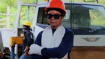 Skillful metal worker with his arms crossed and looks at the camera at workshop while wearing safety equipment. video