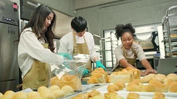 tre giovani amici e partner di avvio di pasta per il pane e pasticcini impegnati con lavori di pasticceria fatti in casa mentre cucinano ordini online, imballano e consegnano in panetteria, piccolo imprenditore video