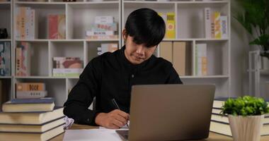 portret van uitgeputte aziatische zakenman die schrijft en handen scheurt papier terwijl hij aan het bureau van de werkplek zit in het kantoor aan huis. slecht werken mislukt, geen idee, mislukt concept. video