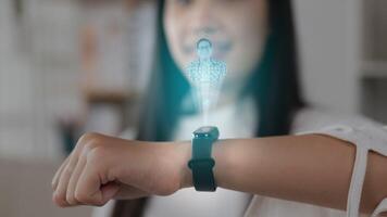 close-up hand van aziatische vrouw die op de slimme horloge drukt terwijl ze op de bank zit. zichtbaar ar-scherm projecteren en chatten tijdens een videogesprek. futuristisch en technologisch concept. video
