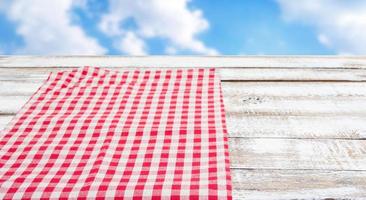 red tablecloth on empty wooden table, blurred sky background