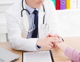 healthcare and medical concept - doctor with patient measuring pulse. Medical insurance. Doc sitting in cabinet. Man in white uniform. photo